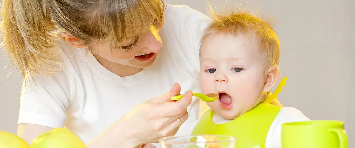 мама кормит малыша с ложки